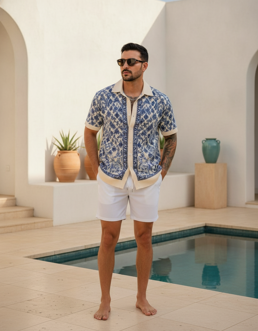 Full-length image of a diverse man wearing a structured knit beach shirt, standing in a modern, minimalist luxury resort sett